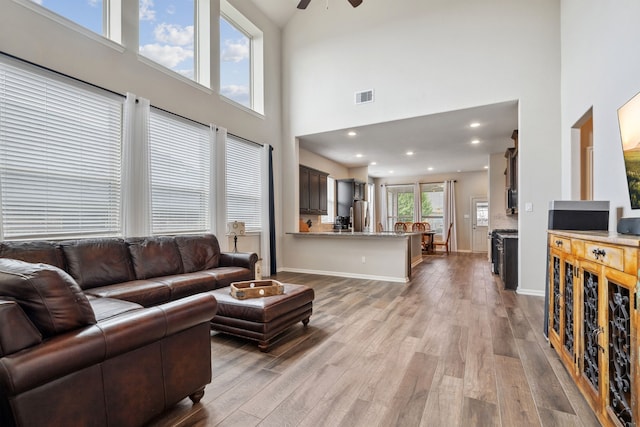 237 Catoti Cay Ct, Conroe, TX 77304 - living area featuring a towering ceiling, light wood finished floors, a ceiling fan, and baseboards
