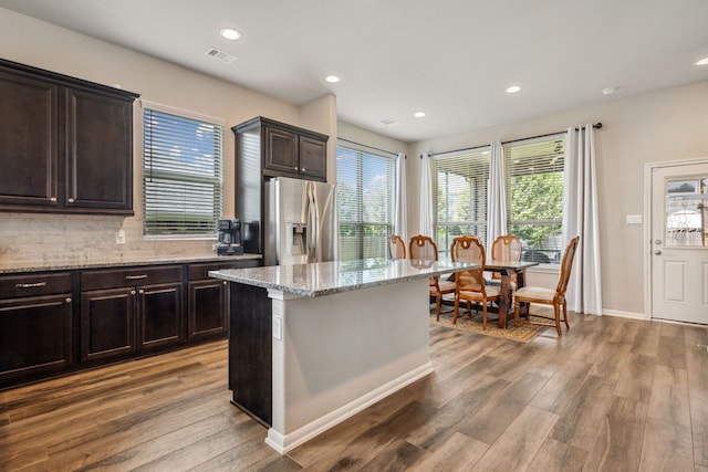 237 Catoti Cay Ct, Conroe, TX 77304 - kitchen with stainless steel fridge with ice dispenser, wood finished floors, light stone countertops, recessed lighting, and tasteful backsplash