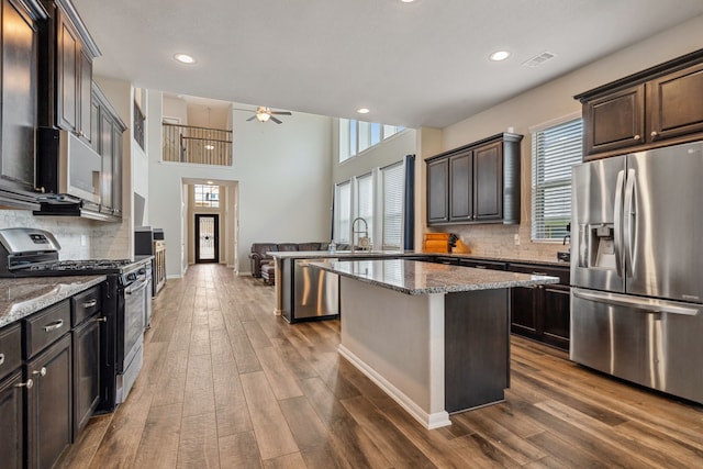 237 Catoti Cay Ct, Conroe, TX 77304 - kitchen featuring appliances with stainless steel finishes, ceiling fan, a peninsula, dark brown cabinetry, and healthy amount of natural light