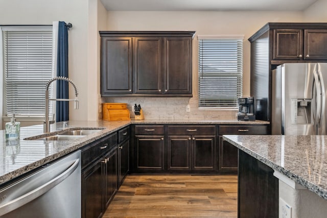 237 Catoti Cay Ct, Conroe, TX 77304 - kitchen with stainless steel appliances, a sink, light stone countertops, wood finished floors, and dark brown cabinetry