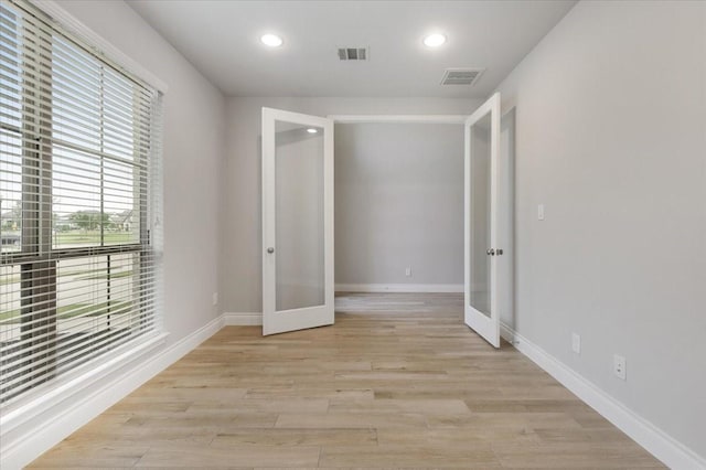 empty room featuring french doors, baseboards, recessed lighting, and light wood-type flooring