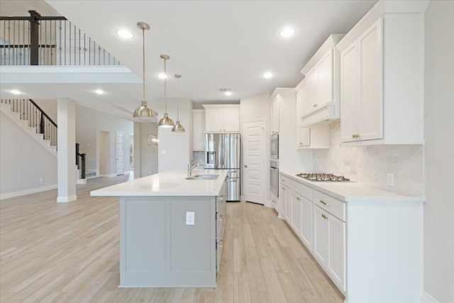 kitchen with stainless steel appliances, a sink, light wood-style floors, baseboards, and light countertops