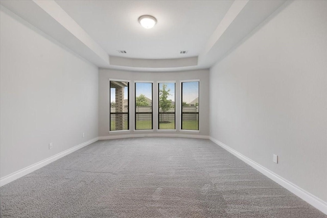 carpeted empty room featuring baseboards and a raised ceiling