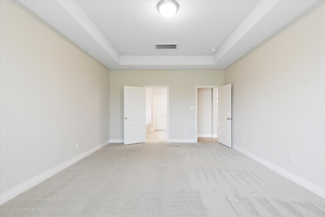 unfurnished bedroom with a tray ceiling, light carpet, and baseboards