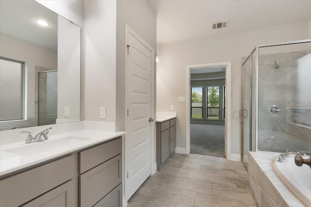 bathroom with a stall shower, vanity, a garden tub, baseboards, and recessed lighting