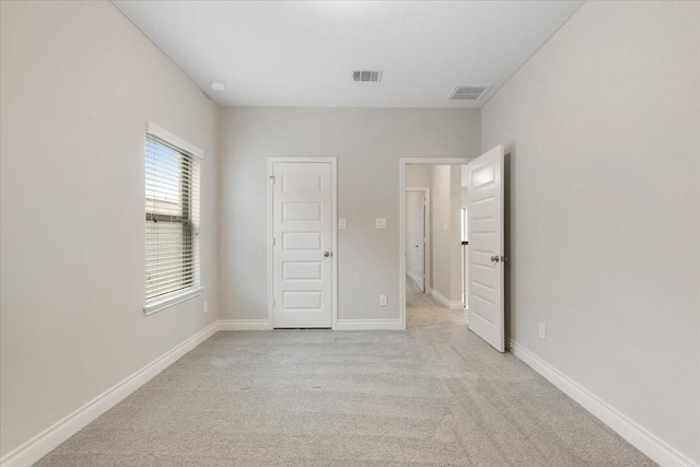 unfurnished bedroom featuring light carpet and baseboards