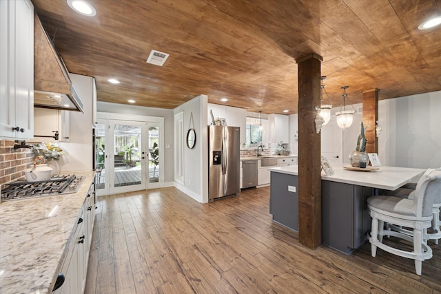 41103 Mill Creek Rd, Magnolia, TX 77354 - kitchen featuring stainless steel appliances, wooden ceiling, dark wood-style floors, hanging light fixtures, and white cabinets