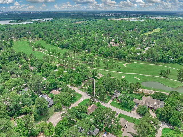 view of property location featuring a nearby body of water, a local golf course, and a heavily wooded area