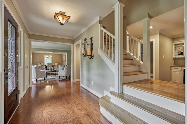 entrance foyer featuring wood finished floors, crown molding, stairway, and baseboards