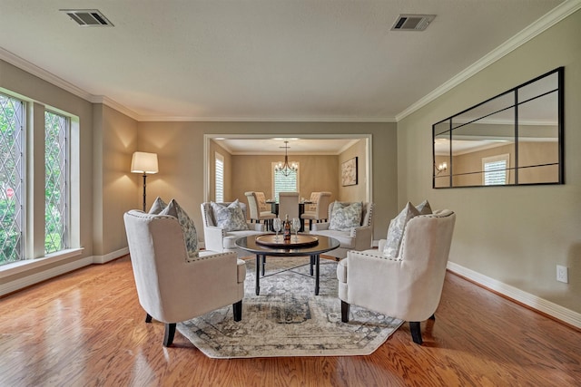 living room with baseboards, wood finished floors, a chandelier, and crown molding