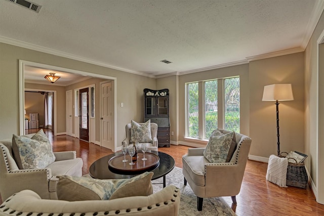 living room with a textured ceiling, crown molding, wood finished floors, and baseboards