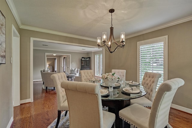 dining room featuring a chandelier, wood finished floors, crown molding, and baseboards