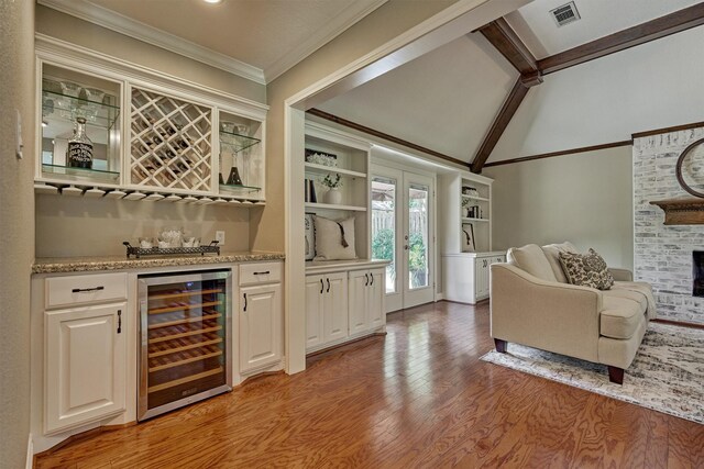 indoor dry bar featuring wine cooler, light wood finished floors, a brick fireplace, and crown molding