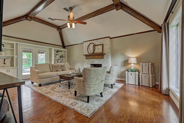 living area with a fireplace, ceiling fan, beam ceiling, wood finished floors, and french doors