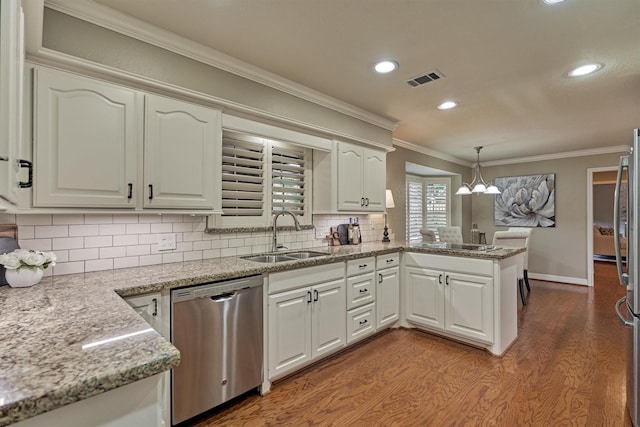kitchen featuring dishwasher, a sink, crown molding, wood finished floors, and a peninsula