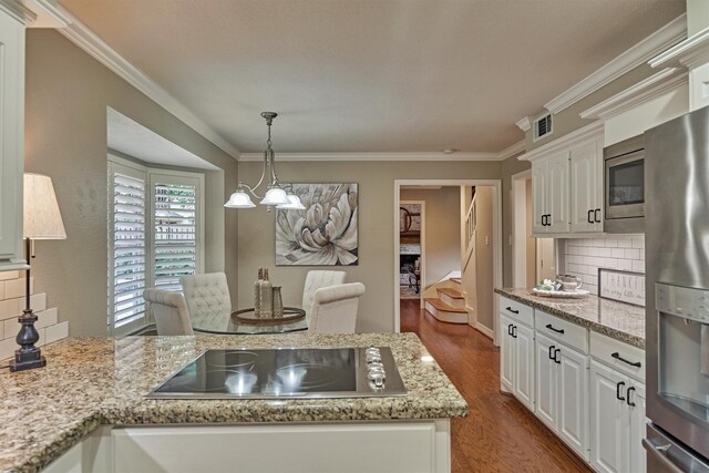 kitchen with appliances with stainless steel finishes, wood finished floors, ornamental molding, tasteful backsplash, and white cabinets
