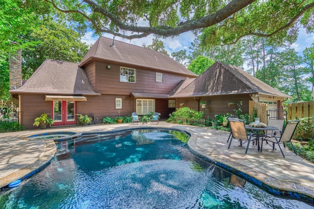 view of swimming pool with french doors, a patio, a pool with connected hot tub, and fence