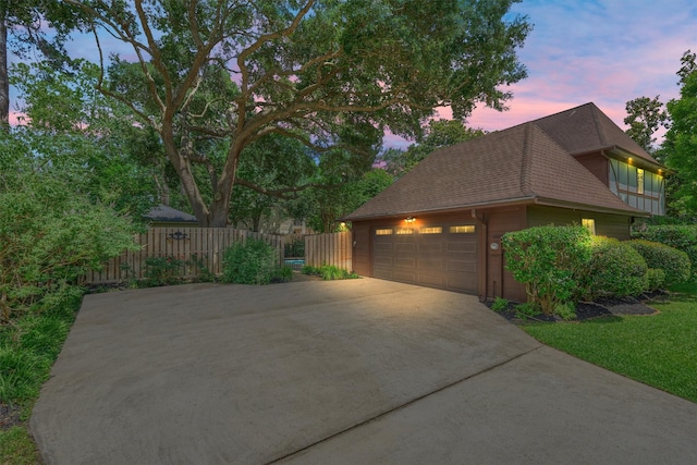view of home's exterior featuring fence, driveway, and a shingled roof