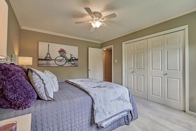 bedroom featuring light colored carpet, crown molding, a closet, and a ceiling fan