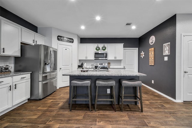 kitchen featuring appliances with stainless steel finishes, a kitchen breakfast bar, recessed lighting, white cabinetry, and light stone countertops