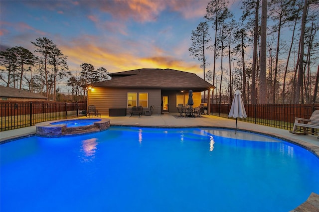 pool at dusk featuring outdoor dining space, a fenced backyard, a pool with connected hot tub, and a patio area