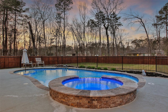 pool at dusk with a fenced backyard, view of scattered trees, and a pool with connected hot tub