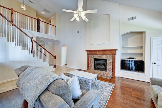 14022 Ashland Landing Dr, Cypress, TX 77429 - living area featuring built in features, stairway, a towering ceiling, ceiling fan, and a brick fireplace