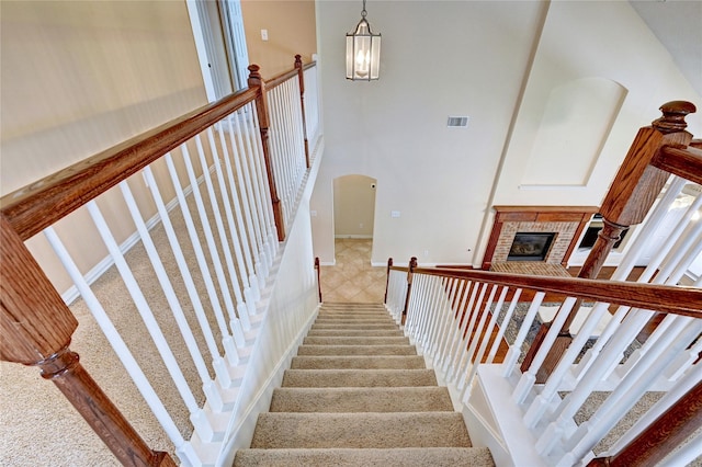 14022 Ashland Landing Dr, Cypress, TX 77429 - staircase featuring a brick fireplace, arched walkways, and a chandelier