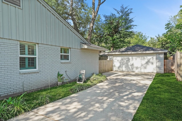 view of side of property featuring board and batten siding, brick siding, fence, and a detached garage