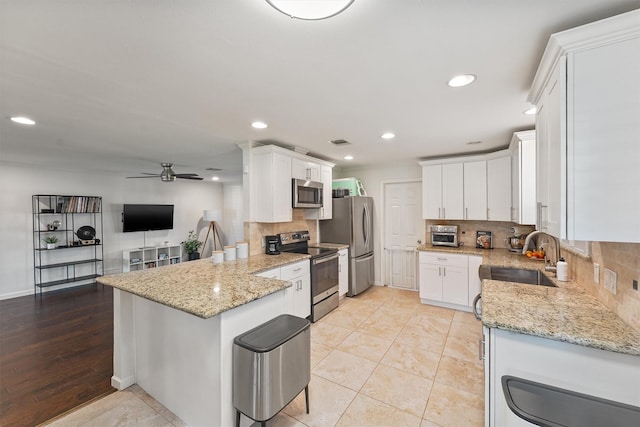 kitchen featuring stainless steel appliances, a sink, a ceiling fan, white cabinetry, and recessed lighting