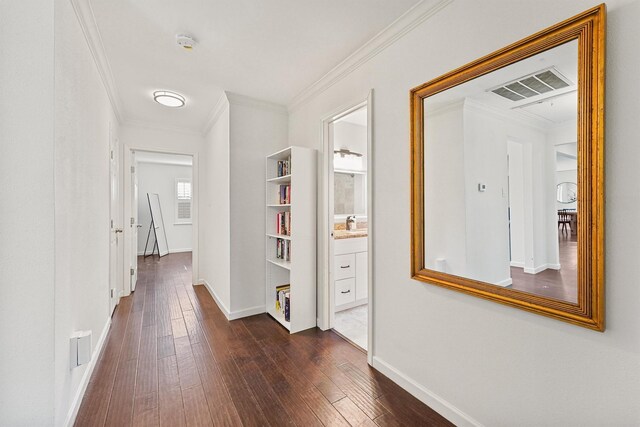 hall with dark wood-style flooring, ornamental molding, and baseboards
