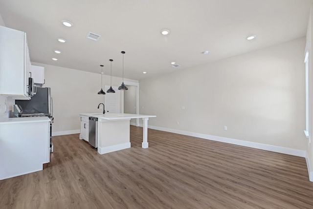 206 S 4th St, Conroe, TX 77301 - kitchen with a center island with sink, wood finished floors, white cabinetry, appliances with stainless steel finishes, and baseboards