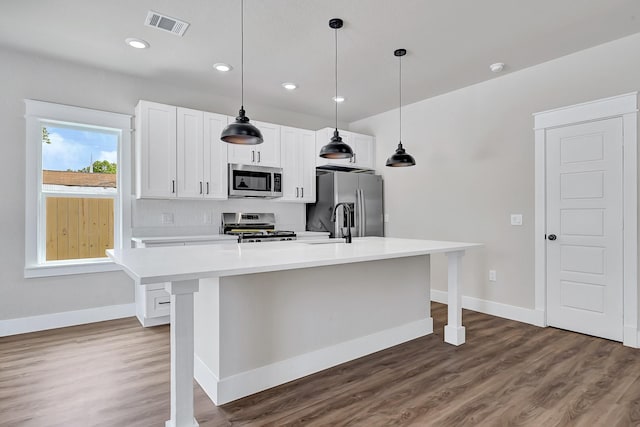206 S 4th St, Conroe, TX 77301 - kitchen featuring stainless steel appliances, a kitchen island with sink, light countertops, wood finished floors, and a breakfast bar area