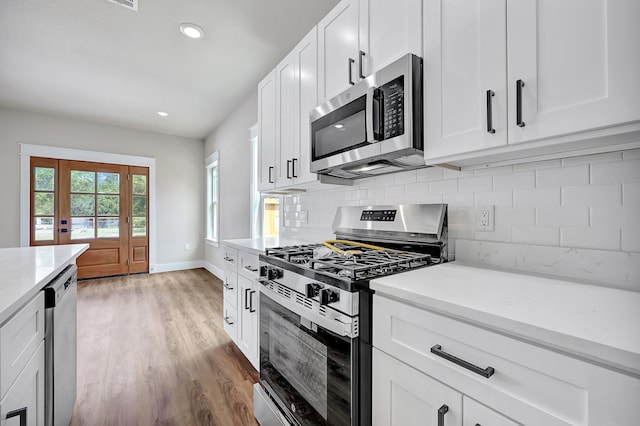 206 S 4th St, Conroe, TX 77301 - kitchen with appliances with stainless steel finishes, tasteful backsplash, light wood finished floors, white cabinetry, and baseboards