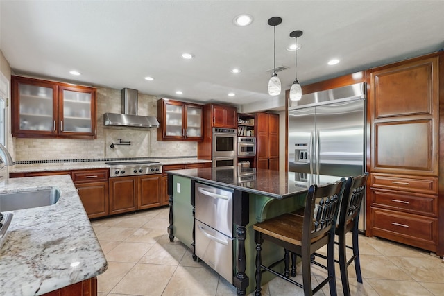 kitchen featuring wall chimney range hood, a sink, appliances with stainless steel finishes, a kitchen island, and light tile patterned floors