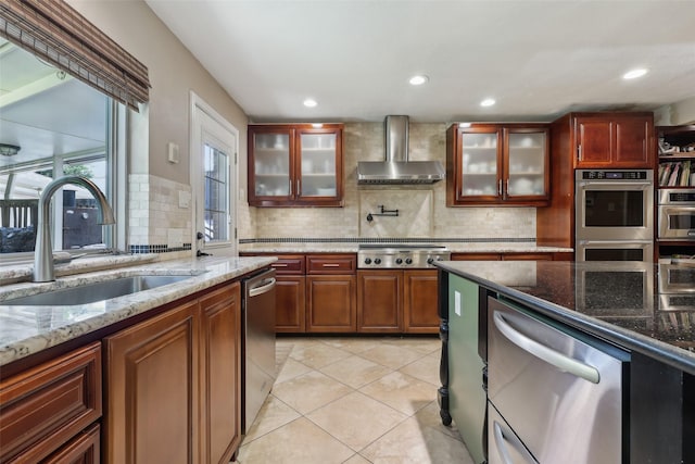 kitchen featuring wall chimney exhaust hood, a sink, appliances with stainless steel finishes, backsplash, and recessed lighting