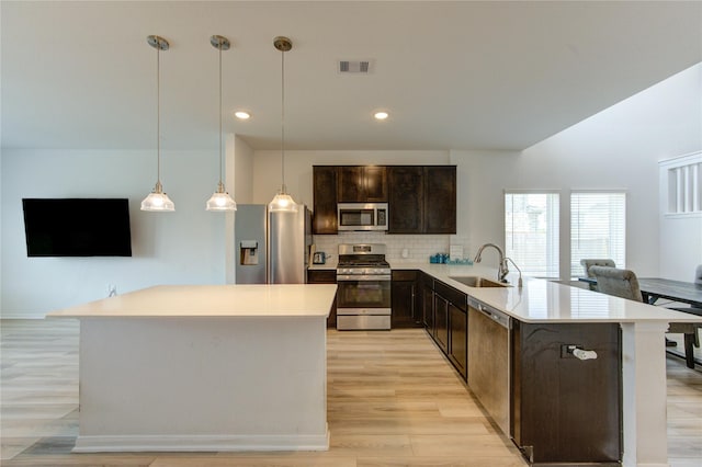 20951 New Proper Dr, New Caney, TX 77357 - kitchen featuring appliances with stainless steel finishes, a sink, dark brown cabinetry, decorative backsplash, and light countertops