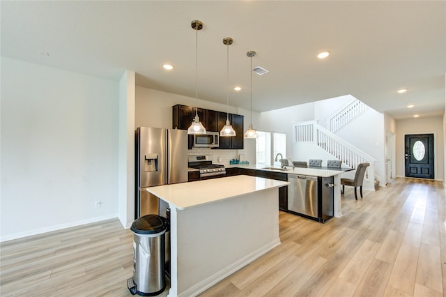20951 New Proper Dr, New Caney, TX 77357 - kitchen with stainless steel appliances, a sink, light wood-type flooring, a peninsula, and a center island