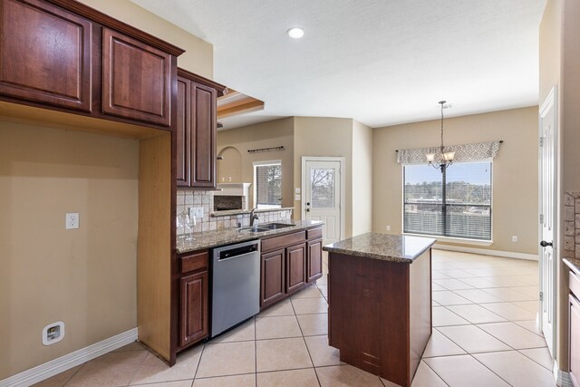 kitchen featuring stainless steel dishwasher, a sink, a chandelier, decorative backsplash, and light stone counters