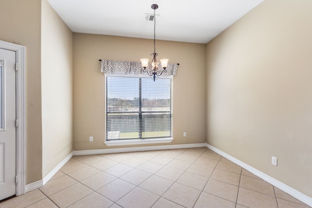 empty room with a chandelier, light tile patterned floors, and baseboards