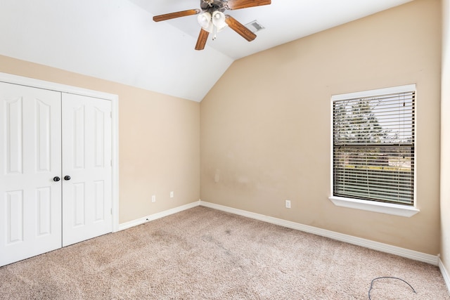 unfurnished bedroom featuring vaulted ceiling, carpet flooring, a closet, baseboards, and a ceiling fan