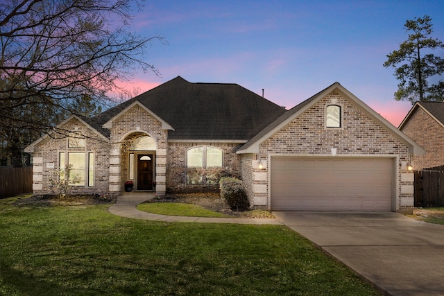 french country home with brick siding, an attached garage, driveway, and roof with shingles