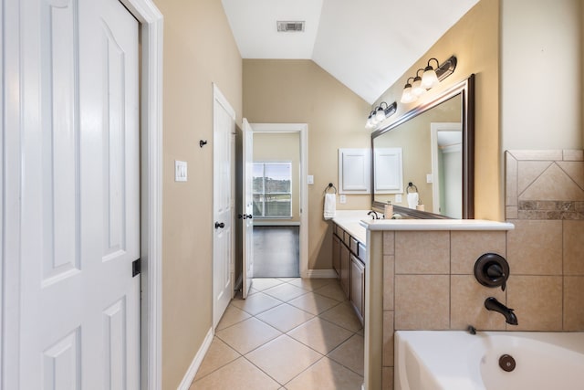 bathroom with tile patterned flooring, a bathtub, vanity, vaulted ceiling, and baseboards