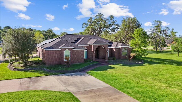 103 Deer Trl, Lake Jackson, TX 77566 - ranch-style house with a front yard, solar panels, brick siding, and a shingled roof