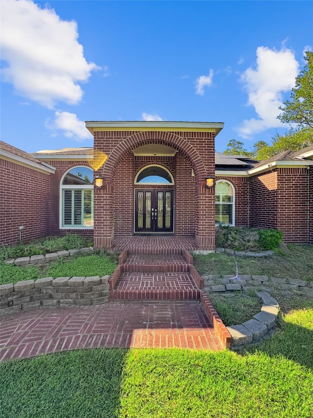 103 Deer Trl, Lake Jackson, TX 77566 - view of exterior entry with french doors, brick siding, and roof mounted solar panels