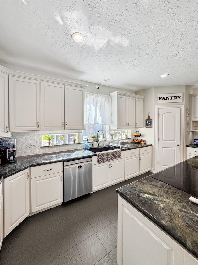 103 Deer Trl, Lake Jackson, TX 77566 - kitchen featuring stainless steel dishwasher, white cabinetry, a sink, a textured ceiling, and dark stone counters