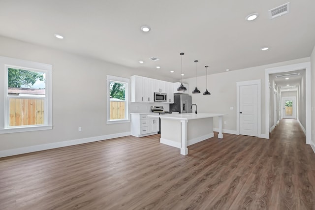 204 S 4th St, Conroe, TX 77301 - kitchen with appliances with stainless steel finishes, white cabinets, an island with sink, light countertops, and a breakfast bar area