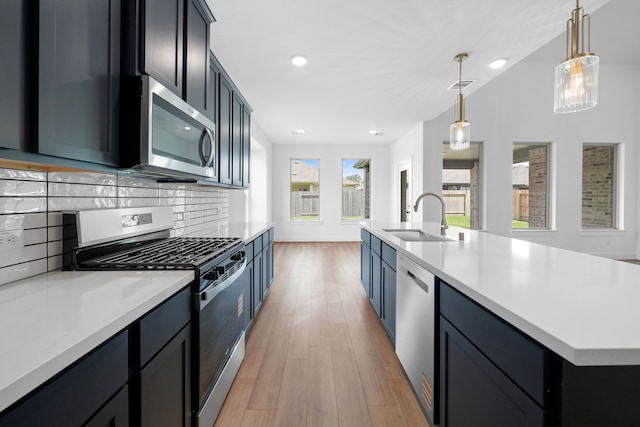 21705 Southern Valley Ln, New Caney, TX 77357 - kitchen with appliances with stainless steel finishes, light countertops, light wood-style flooring, backsplash, and pendant lighting