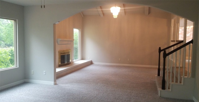 unfurnished living room with a glass covered fireplace, carpet flooring, healthy amount of natural light, and stairs