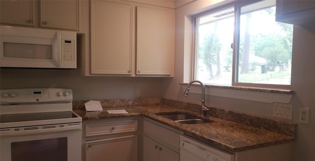 kitchen with white appliances, a sink, plenty of natural light, and white cabinetry